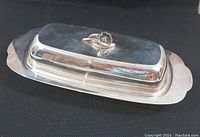 Full view of silver plated butter dish with lid showing the entire plate and floral knob on top.