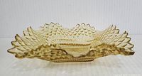 Side view of amber tinted square Federal Glass candy dish with diamond point pattern and ruffled scalloped edges.