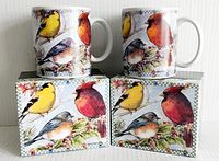 Two Lang and Wise coffee mugs with colorful bird illustrations, displayed with their original boxes featuring matching artwork.