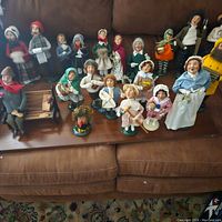 Single image showing all 20 Byers Choice caroler figurines displayed on sofa and coffee table.