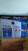 Box of Therapure air purifier showing front with product image and key features.