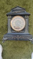 Full front view of black antique Ansonia mantle clock with gold accents and decorative elements.