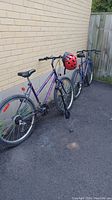 Two CCM 18 speed bicycles, one purple and one blue, side by side outdoors.