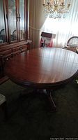 Oval wooden dining table with two leaves viewed from top showing finish and shape.