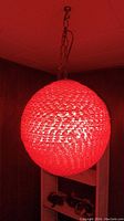 Red spherical hanging ball lamp glowing red, hanging by metal chain