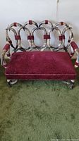 Front view of the settee showing full horn frame and red velvet seat
