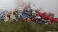 Wide view showing an assortment of ceramic and glass knick knacks including colorful animal figurines, vases, and decorative bowls on a green carpet.