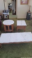 Overview of all three tables arranged on a carpeted floor showing marble tops and wooden bases.