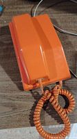 Top view of orange plastic telephone handset showing sleek mid-century design and coiled cord.