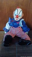 Front view of the clown figurine seated against a wooden background showing detailed features and costume
