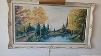 Full view of the framed oil painting showing the landscape of trees, pond, and pathway with soft sky.