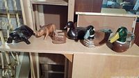 Six wooden animal figurines displayed on wooden shelves: turtle, rhino, deer, and three ducks.