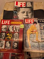 Three Life magazines partially stacked, showing the October 20, 1961 issue with 'Communism' headline, the November 1983 issue with John F. Kennedy cover, and the December 1, 1961 issue