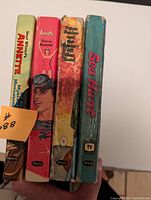 Four vintage books spines showing titles: Annette Mystery at Moonstone Bay, Annette Sierra Summer, Trixie Belden and the Mystery Off Glen Road, Sea Hunt