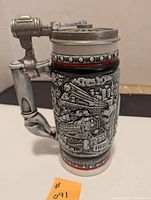 Front and side view of the Avon beer stein showing embossed detailed train design, pewter lid, and color banding.