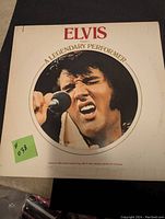 Front cover of Elvis Presley A Legendary Performer Volume 1 album showing Elvis singing with microphone, white cover with red text.