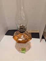 Full view of the oil lamp showing the clear glass chimney and the amber gold faceted glass base.