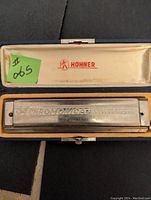 Hohner 64 Chromonica harmonica inside blue case with yellow velvet lining and Hohner logo in lid. Shows engraved text and condition.