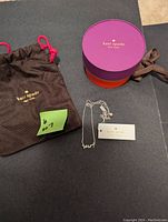 Wide shot showing the Kate Spade necklace with pouch and round box