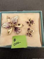 Overview of the lily brooch and two matching earrings presented in a box with a soft inner lining.