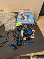 Blue M&M character radio figure with wired headphones, original box in background.