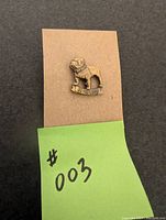 Front view of the Mack Truck bulldog lapel pin attached to a display cardboard with a small green note showing '#003'.