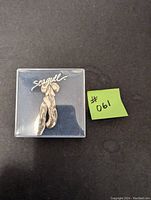 Front view of pewter ballerina slippers brooch in a plastic case with Seagull branded backing
