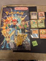 Clear image of the Nintendo Pokemon poster and six Pokemon cards laid out on a flat surface.