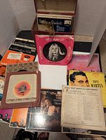 Wooden red Disc-O-Mate record case open showing vintage 45 RPM vinyl records inside with colorful sleeves and albums by artists such as Tony Martin and Dorothy Bower