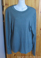 Front view of gray-green knit Calvin Klein Jeans sweater on mannequin, showing relaxed fit and crew neckline.