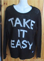 Front view of black lightweight knit sweater with bold white "TAKE IT EASY" lettering on front and round neckline displayed on mannequin.