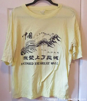 Full front view of yellow T-shirt with Great Wall of China graphic and black text.