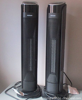 Pair of black Noma oscillating ceramic tower heaters standing upright with cords coiled at the base.