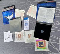 Two Canada Post millennium collectible sets displayed on ground with coins in tins, postage stamps, and official booklets.
