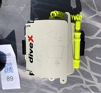 White DiveX wristband note board with pencil on neon yellow coiled wristband, shown outside with visible faint writings.