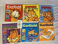 Front cover photo showing all six Garfield Fat Cat 3-Pack books arranged in two rows of three, with bright colorful covers featuring Garfield in various poses.