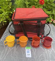 Full lot showing one red and black soft sided cooler bag with shoulder straps, and 4 Tupperware mugs with lids in retro colors lined up in front.