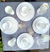Overhead view of four complete place settings with plates, cups, mugs, wineglasses and candlesticks