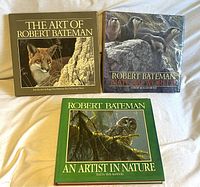 Three Robert Bateman coffee table books displaying cover artwork featuring wildlife including a cougar, otters, and an owl.