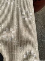Close-up of beige-toned table runner fabric showing subtle floral pattern in woven texture.