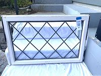 Front view of vintage window showing white wooden frame with diamond patterned leaded glass.