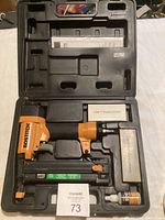 Bostitch SB-21N1 orange and black air nailer in black carrying case with included boxes of staples and oil, lot contents overview.
