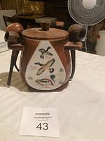 Front view of antique ceramic pipe holder with painted ducks and pipes attached.