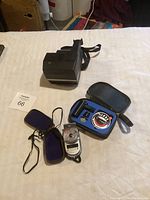 Overview of camera, light meter kit, and flash accessory on table with auction tag.