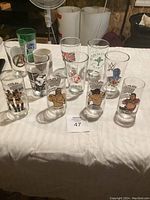 Overview of 10 collectible glasses with wrestling and branded designs arranged on a white cloth surface.