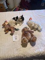 Five assorted collectible stuffed animals including a Ty Beanie Baby moose, black and white cat, white sheep, brown teddy bear with bow, and small dog.