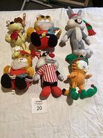Group of six plush cartoon character animals laid out on white surface.