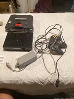 Nintendo 64 console, one controller, power adapter and a Nintendo Wii console on a white surface.