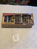 Front view of the boxed 4-pack of The Hangover pint glasses with quotes and character images visible on each glass through the packaging window.