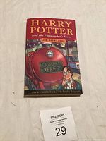 Front cover of the Harry Potter and the Philosopher’s Stone paperback book showing illustration of the Hogwarts Express and Harry Potter.